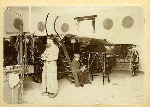 Koetsier met staljongen aan het werk in een koetshuis